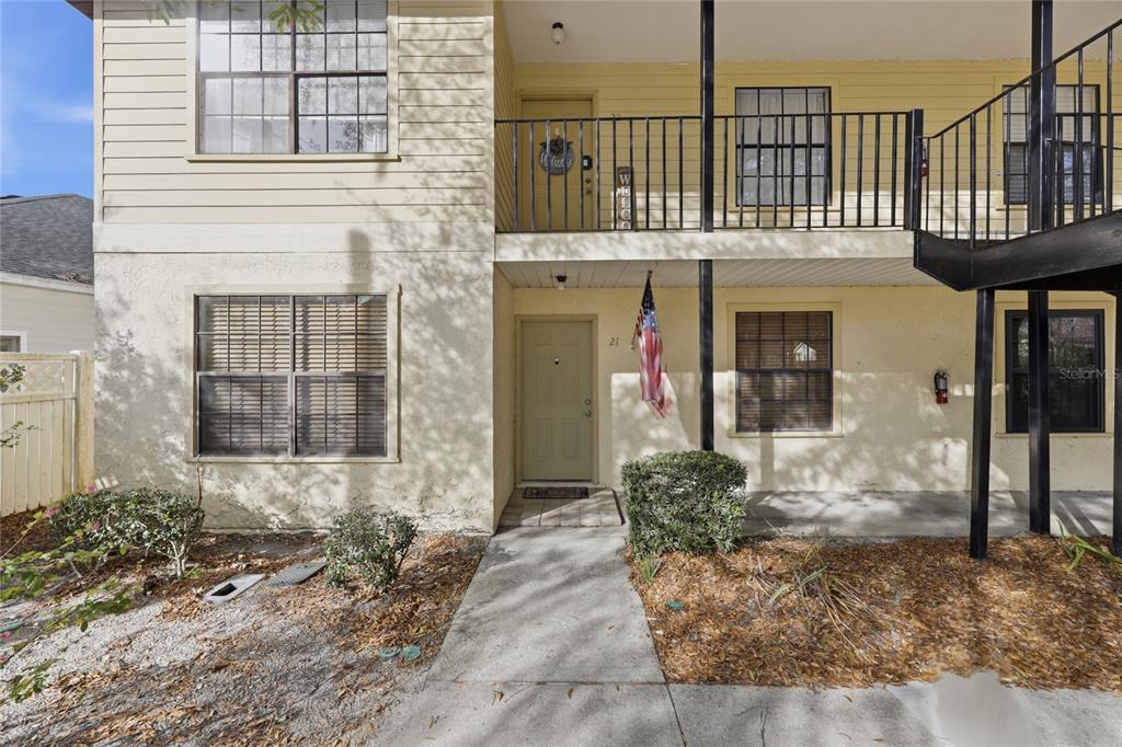 A two-story apartment building exterior features a ground-level entrance with an American flag — 6400 NW 106TH PLACE UNIT 21, ALACHUA, FL