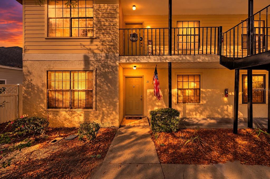 An exterior view of a two-story apartment building with a tan facade and American flag — 6400 NW 106TH PLACE UNIT 21, ALACHUA, FL
