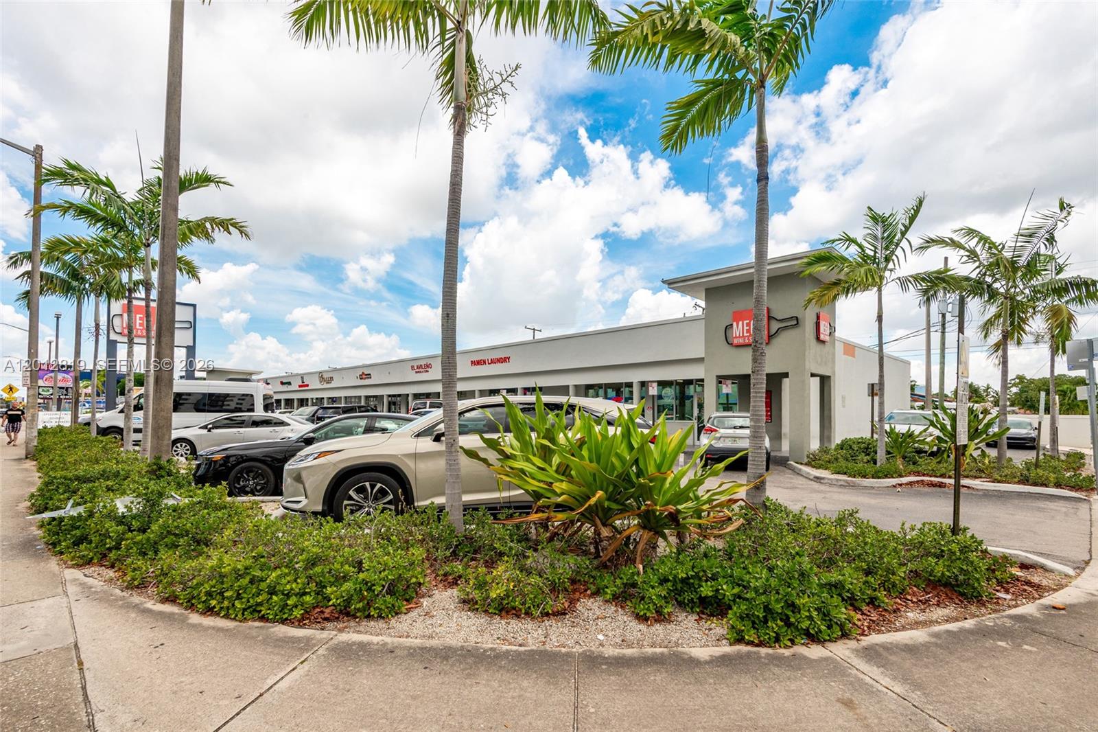 A strip mall features a parking lot, palm trees, and storefronts under a cloudy sky — 3941 NW 7 ST, Miami FL 33126, MIAMI, FL