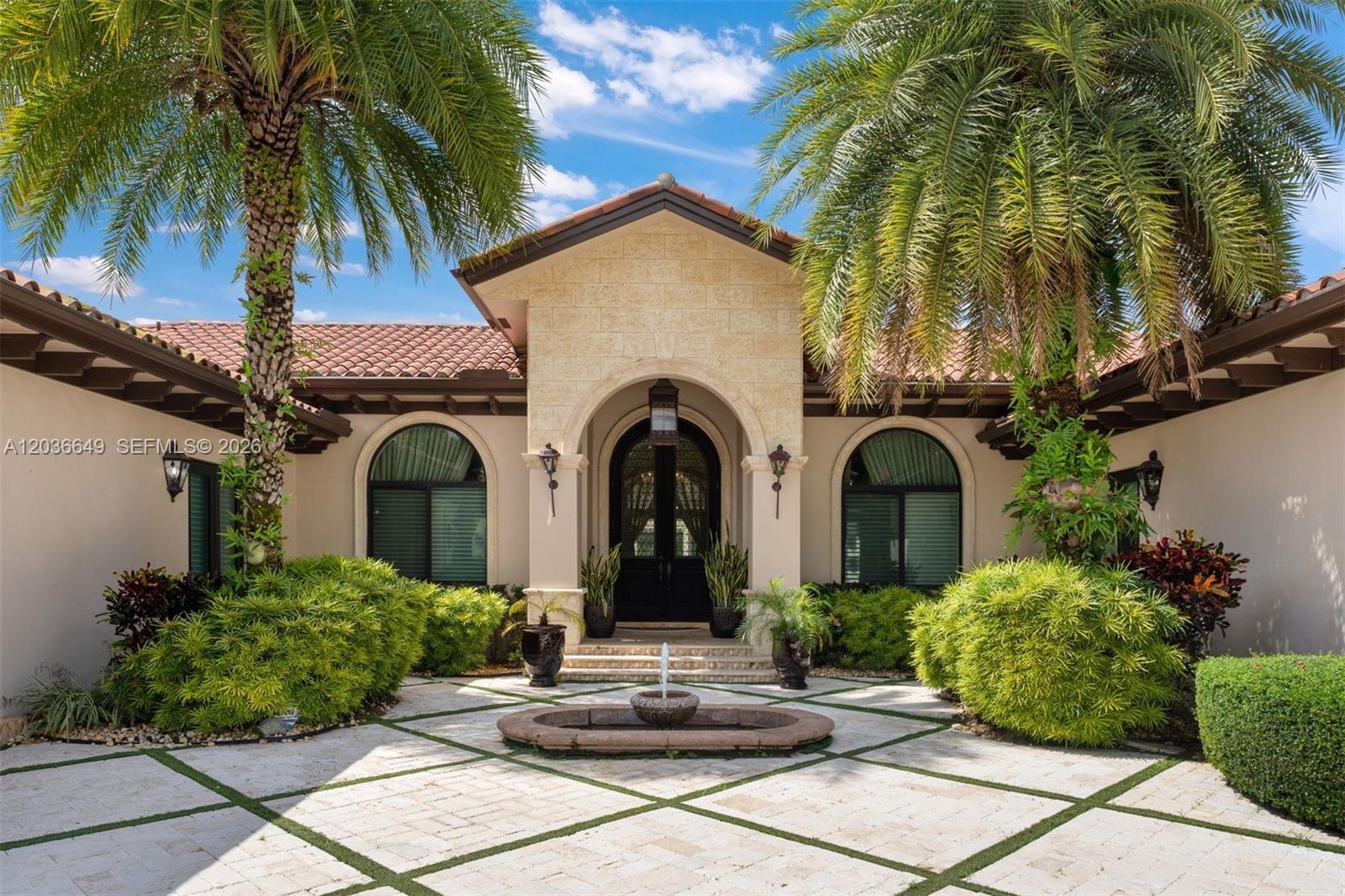 The exterior of a Mediterranean-style home features a stone entryway, a fountain, and palm trees — 10270 SW 62nd St, Miami FL 33173, MIAMI, FL