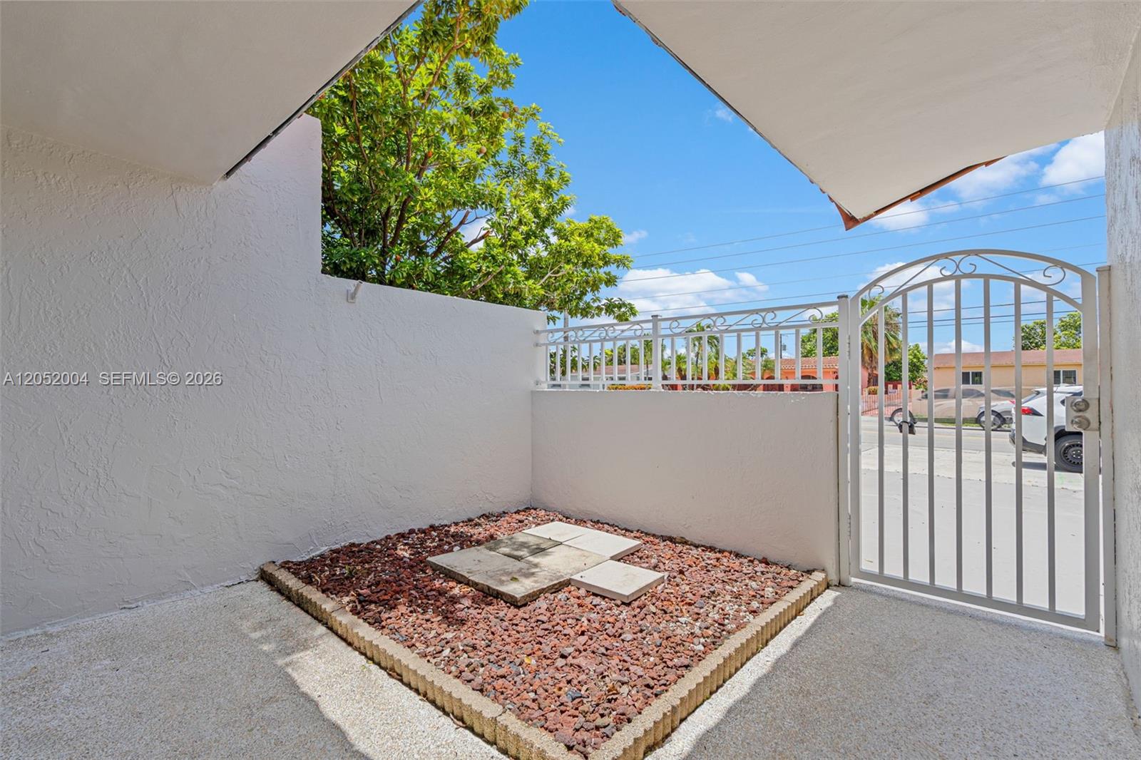A small outdoor patio features a gravel garden bed, concrete pavers, and a metal gate — 1333 W 37th St, Hialeah FL 33012, HIALEAH, FL