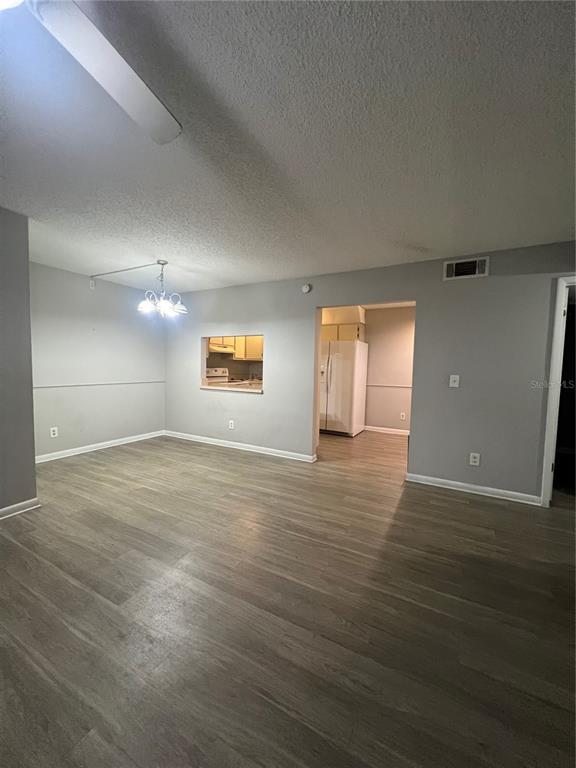 A living area with light gray walls, wood-look flooring, and a pass-through to the kitchen — 1512 S PINE RIDGE CIRCLE, SANFORD, FL
