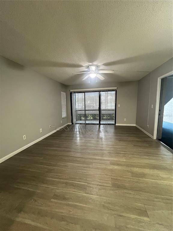 An empty living room features gray walls, wood-look flooring, a ceiling fan, and sliding glass doors — 1512 S PINE RIDGE CIRCLE, SANFORD, FL