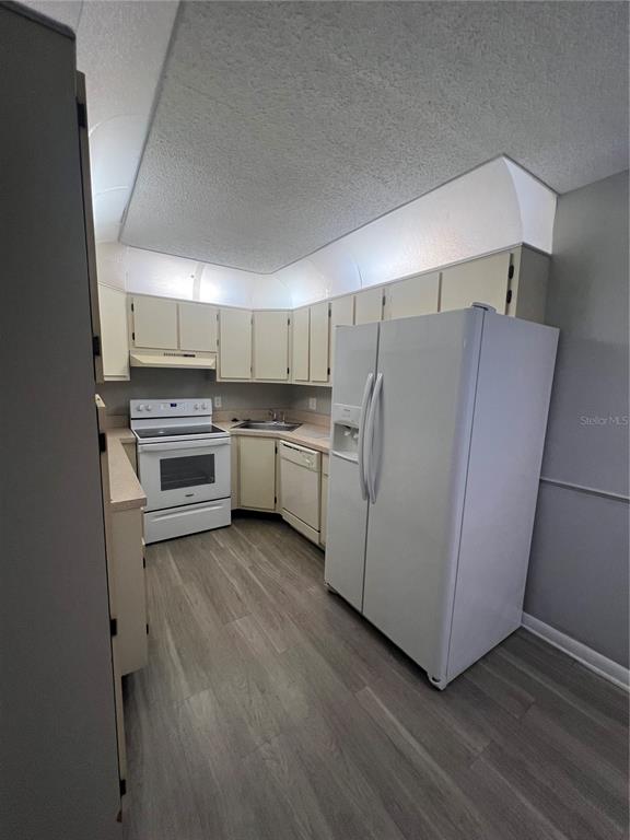 A kitchen features white appliances, light-colored cabinets, and wood-look flooring — 1512 S PINE RIDGE CIRCLE, SANFORD, FL