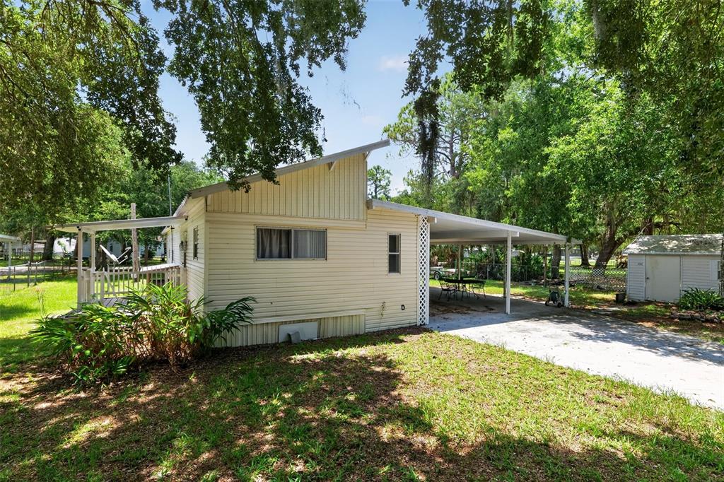 A light-colored mobile home with a carport and a small shed in a grassy yard — 10513 LYNNWOOD AVENUE, LAKE WALES, FL