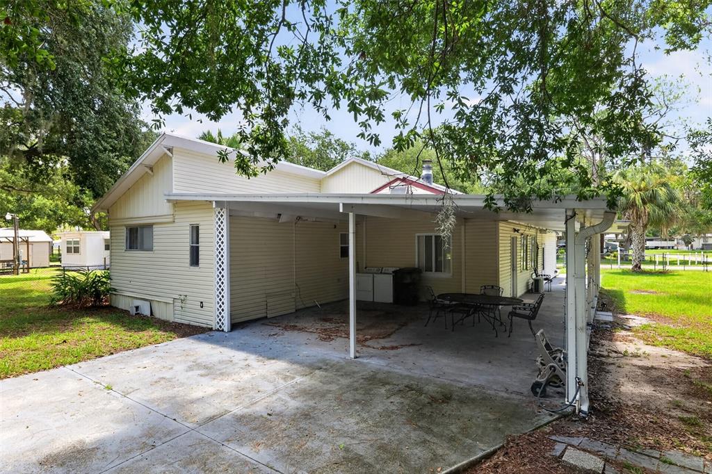 A light-colored house with a large concrete carport and patio area under a metal roof — 10513 LYNNWOOD AVENUE, LAKE WALES, FL