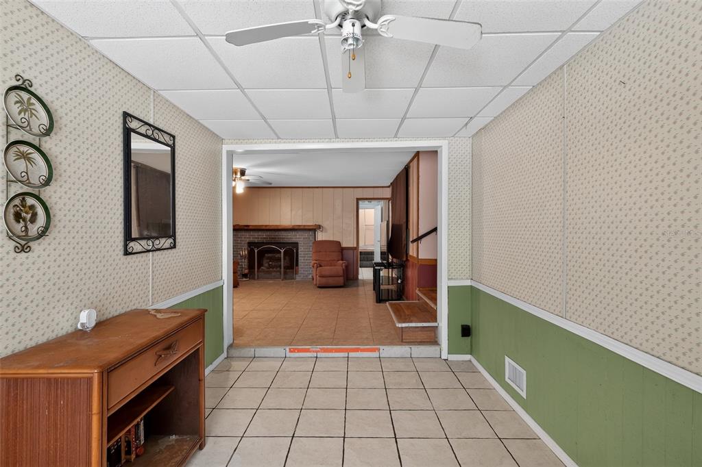 A tiled entryway with patterned wallpaper and green wainscoting leads into a living room — 10513 LYNNWOOD AVENUE, LAKE WALES, FL