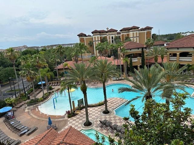 An elevated view of a resort swimming pool surrounded by palm trees and hotel buildings — 12527 FLORIDAYS RESORT DRIVE UNIT 605-E, ORLANDO, FL
