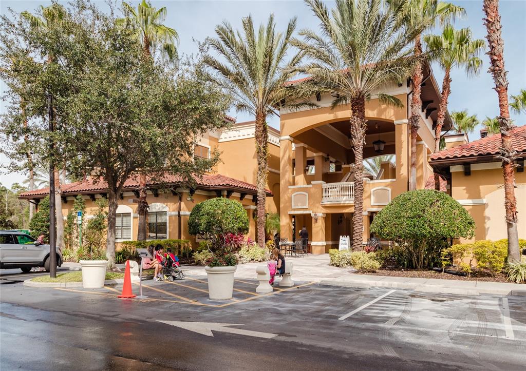 The exterior of a multi-story building features stucco walls, a tile roof, and palm trees — 12527 FLORIDAYS RESORT DRIVE UNIT 605-E, ORLANDO, FL