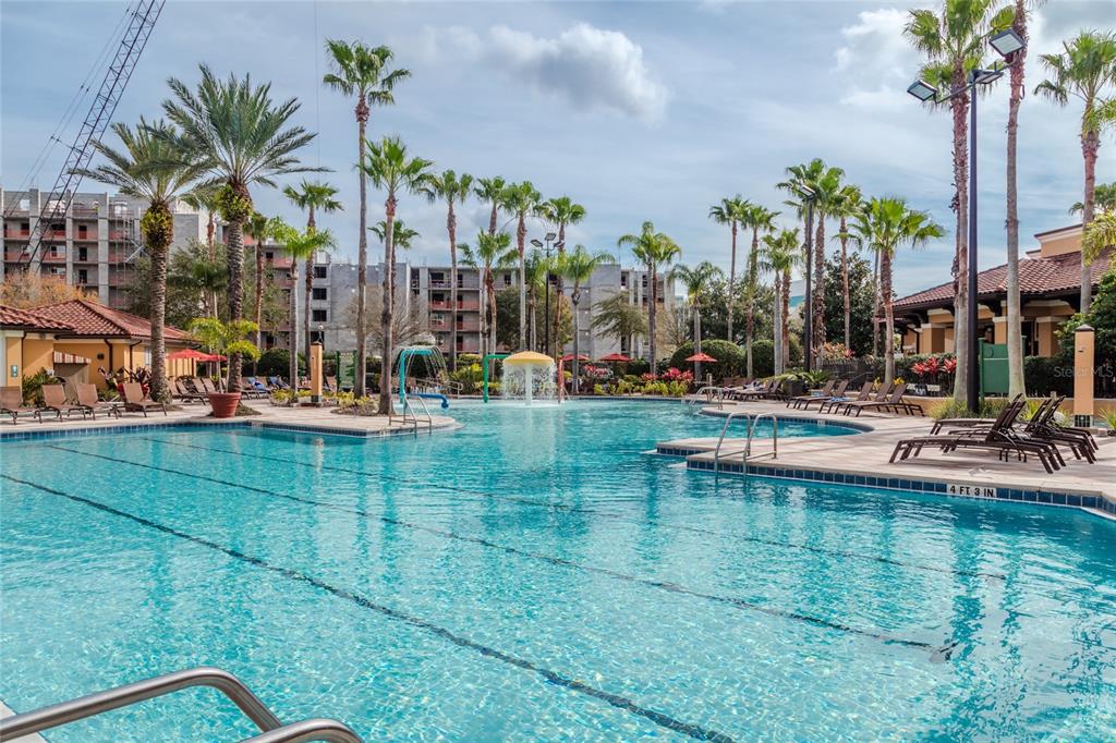 A large outdoor swimming pool with palm trees and a multi-story building under construction nearby — 12527 FLORIDAYS RESORT DRIVE UNIT 605-E, ORLANDO, FL