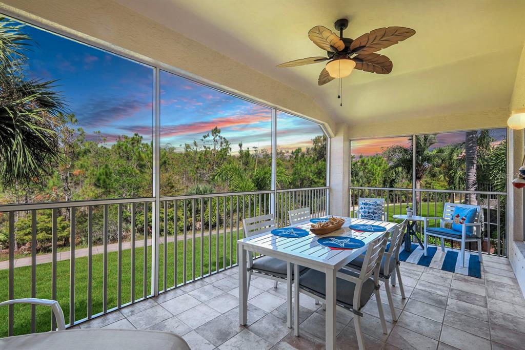 A screened-in patio features a dining set, tile flooring, and a ceiling fan overlooking nature — 11019 MILL CREEK WAY UNIT 901, FORT MYERS, FL