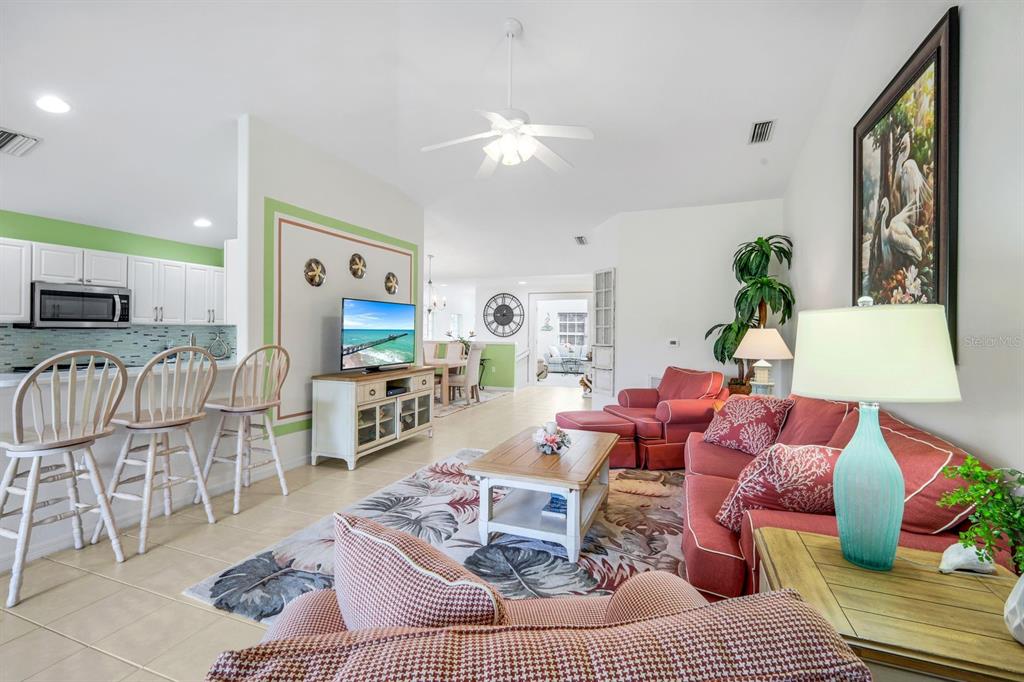 A living room features a red sofa, a television on a console, and bar stools — 11019 MILL CREEK WAY UNIT 901, FORT MYERS, FL