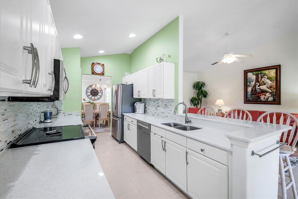 A white kitchen with light green walls features stainless steel appliances and a breakfast bar — 11019 MILL CREEK WAY UNIT 901, FORT MYERS, FL