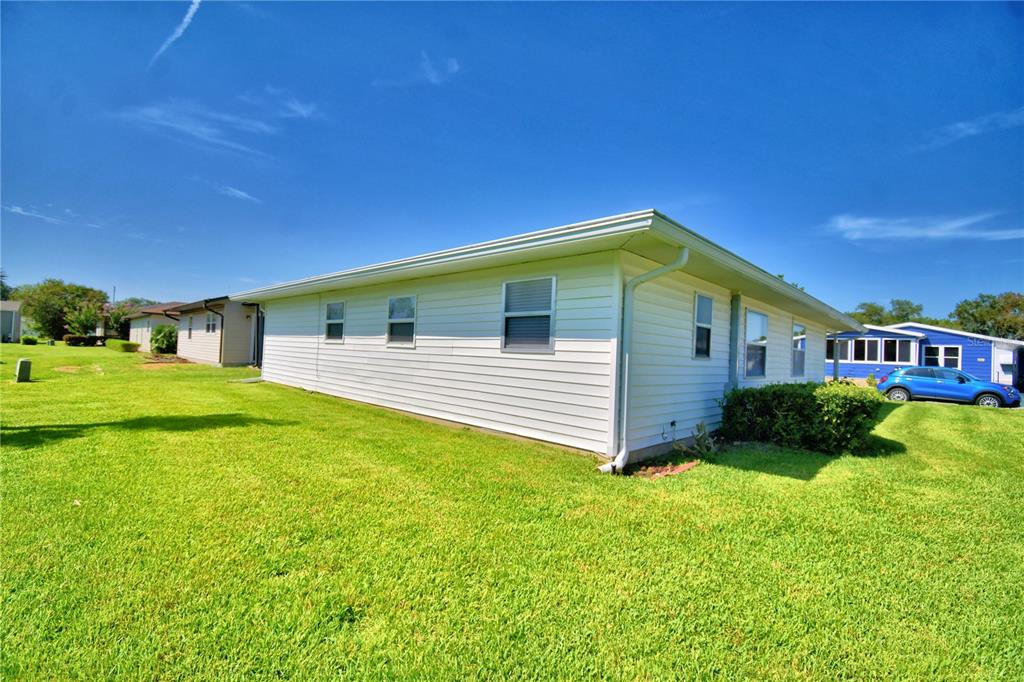 The exterior side view of a white, single-story house with a lawn and blue car — 4860 GOLDENVIEW LANE, LAKELAND, FL