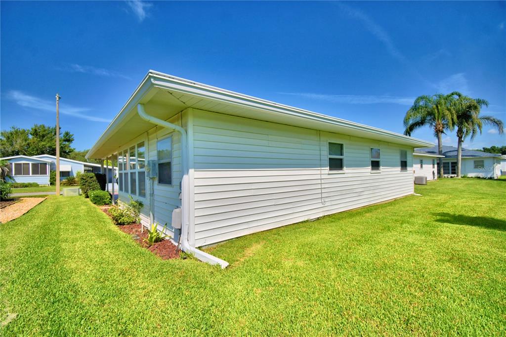 The exterior side view of a white, single-story house with horizontal siding and green lawn — 4860 GOLDENVIEW LANE, LAKELAND, FL