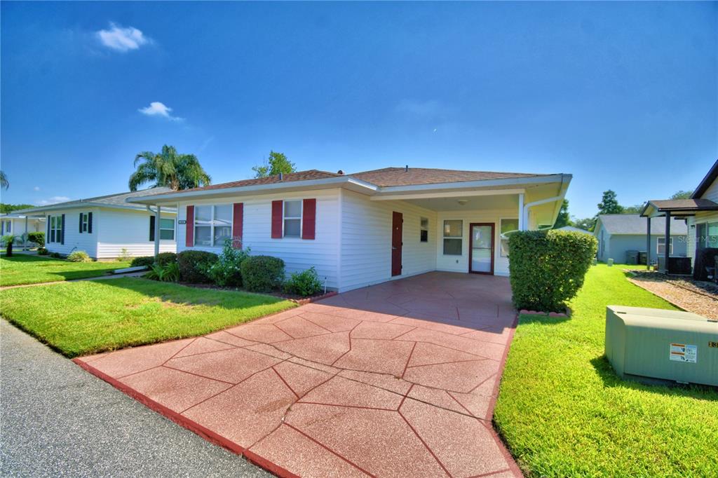 A single-story house with white siding, red shutters, and a stamped concrete carport — 4860 GOLDENVIEW LANE, LAKELAND, FL