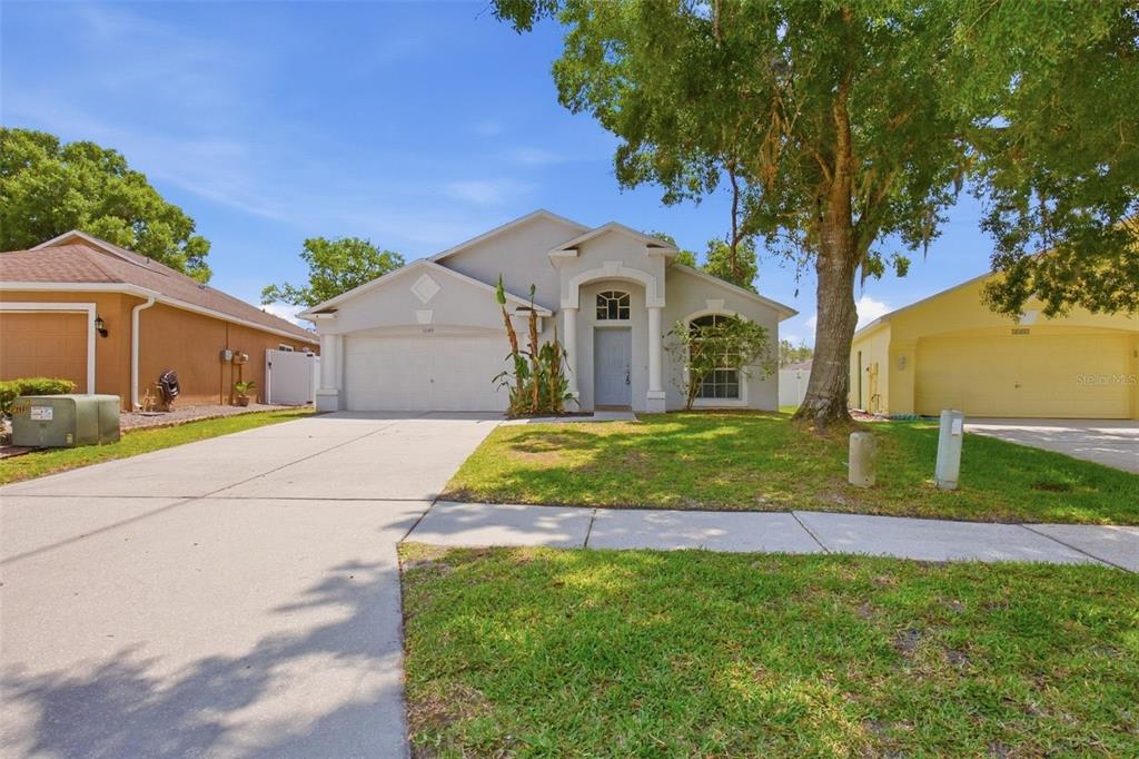 A single-story suburban house with a light gray exterior, a two-car garage, and a lawn — 3049 CASTLE ROCK CIRCLE, LAND O LAKES, FL