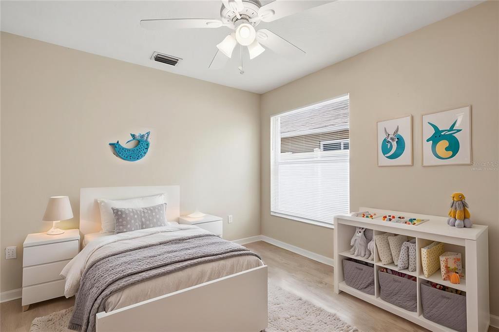 A bedroom with a white bed, a storage unit, and wall art — 3049 CASTLE ROCK CIRCLE, LAND O LAKES, FL