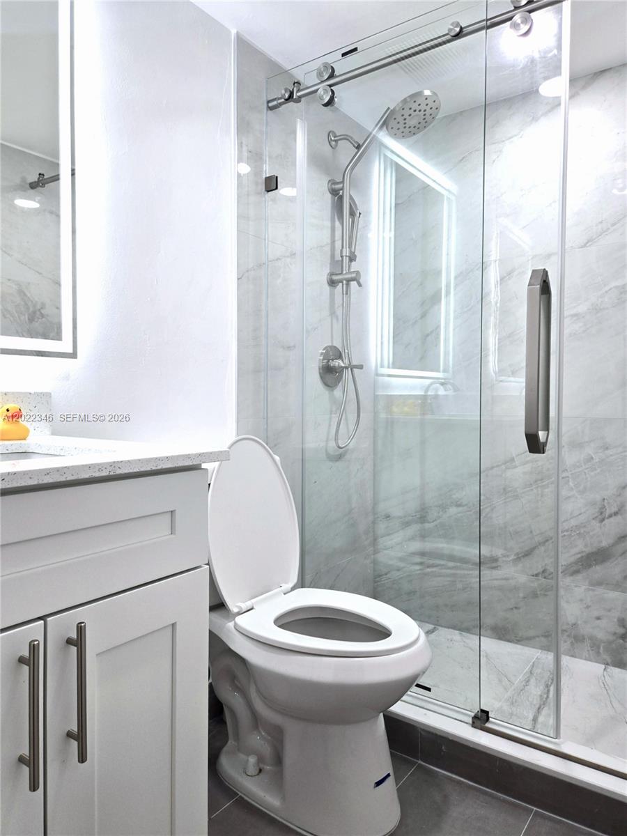 A bathroom features a white vanity, a toilet, and a glass-enclosed walk-in shower — 900 SW 104th Ct # 108, Miami FL 33174, MIAMI, FL