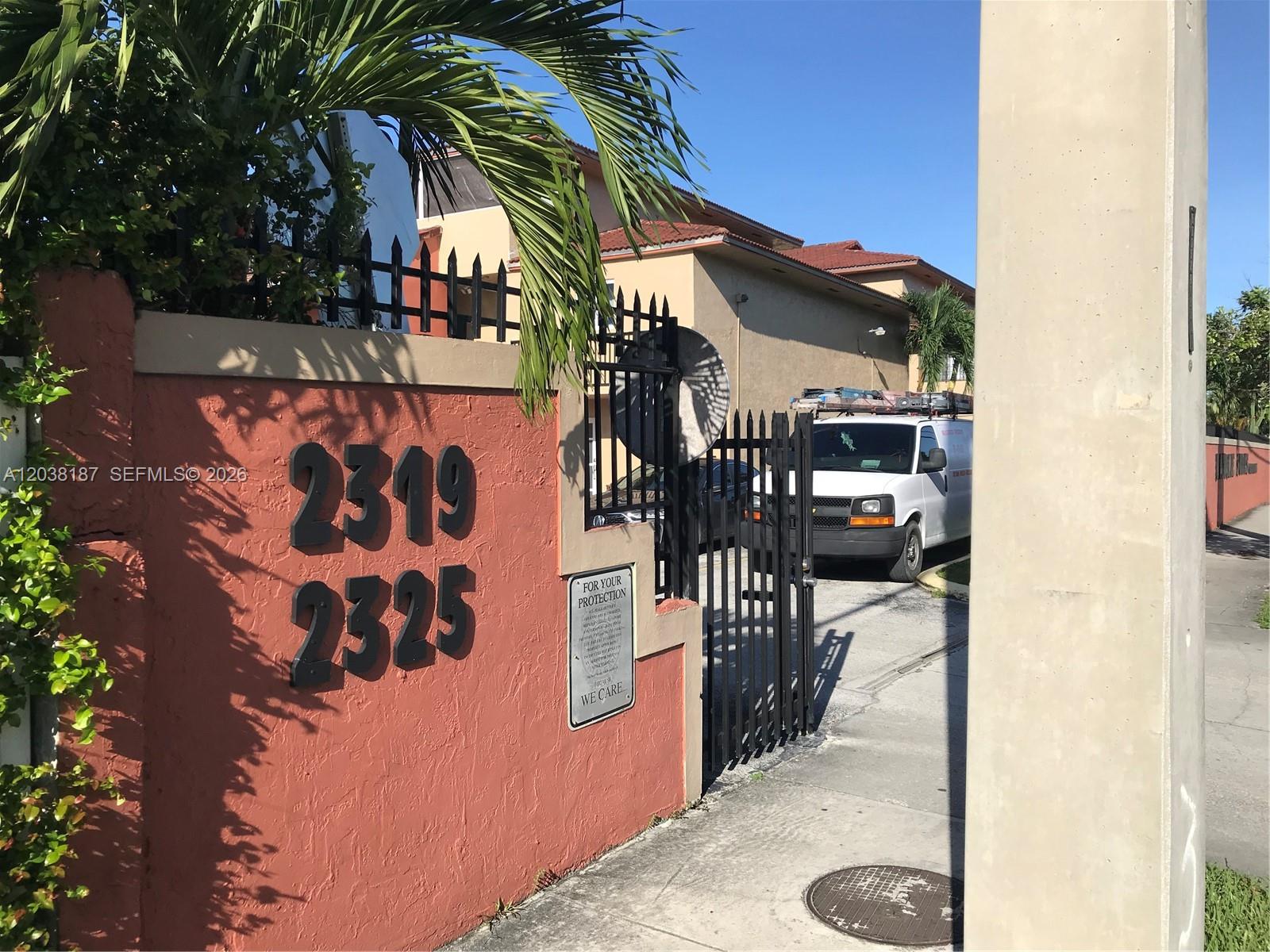 A white work van is parked behind a black metal gate at a gated entrance — 2319 W 60th St # D212, Hialeah FL 33016, HIALEAH, FL