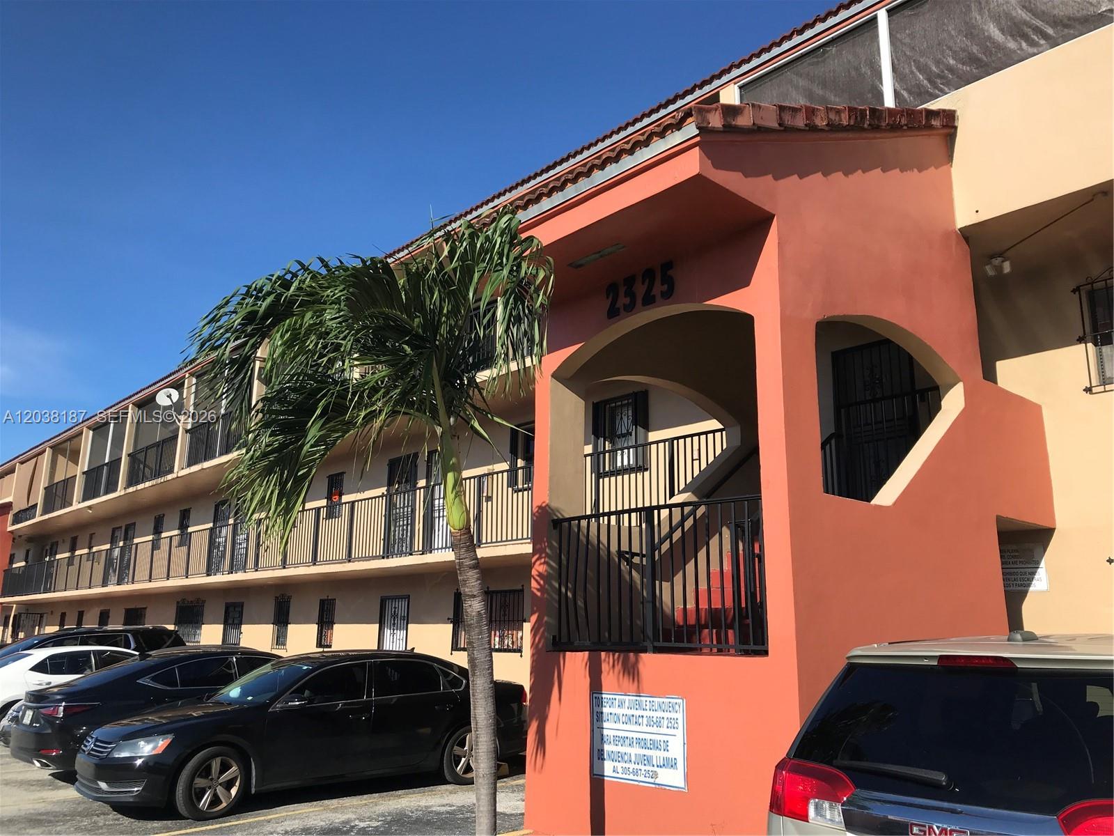 A multi-story apartment building with a peach-colored exterior, an outdoor staircase, and parked cars — 2319 W 60th St # D212, Hialeah FL 33016, HIALEAH, FL