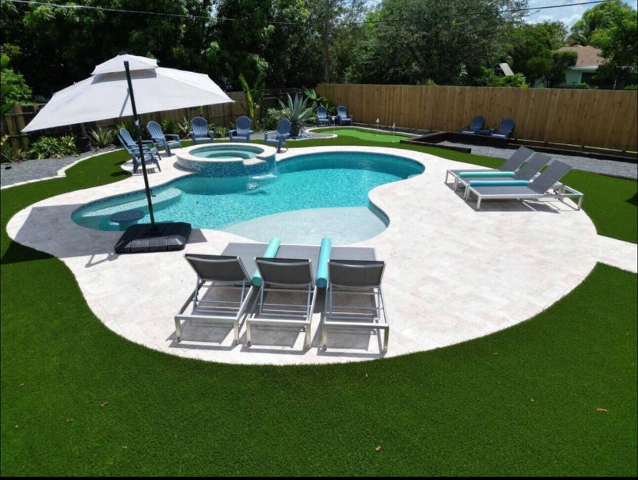 A backyard features a kidney-shaped swimming pool with a spa, stone patio, and artificial turf — 270 NW 36th Street, Boca Raton FL 33431, BOCA RATON, FL