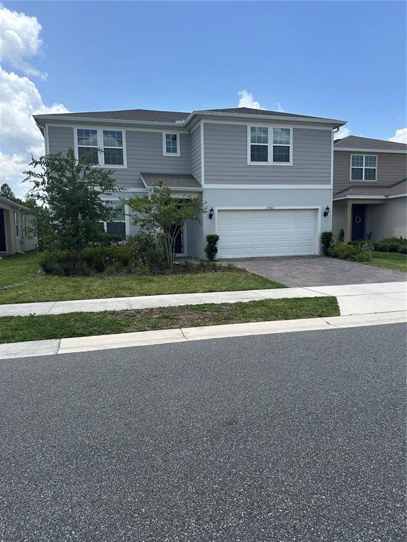 A two-story house with gray siding, a white garage door, and a paved driveway — 17663 SAW PALMETTO AVENUE, CLERMONT, FL