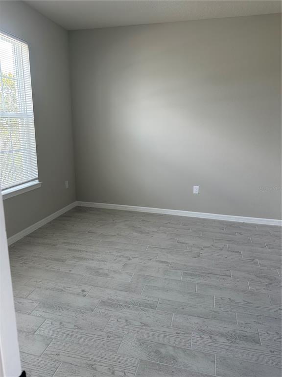 An empty room features light gray walls, wood-look tile flooring, and a single window — 17663 SAW PALMETTO AVENUE, CLERMONT, FL