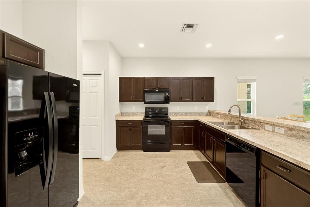 A kitchen featuring dark wood cabinets, black appliances, and light-colored granite countertops — 4680 VIGNETTE WAY, SARASOTA, FL