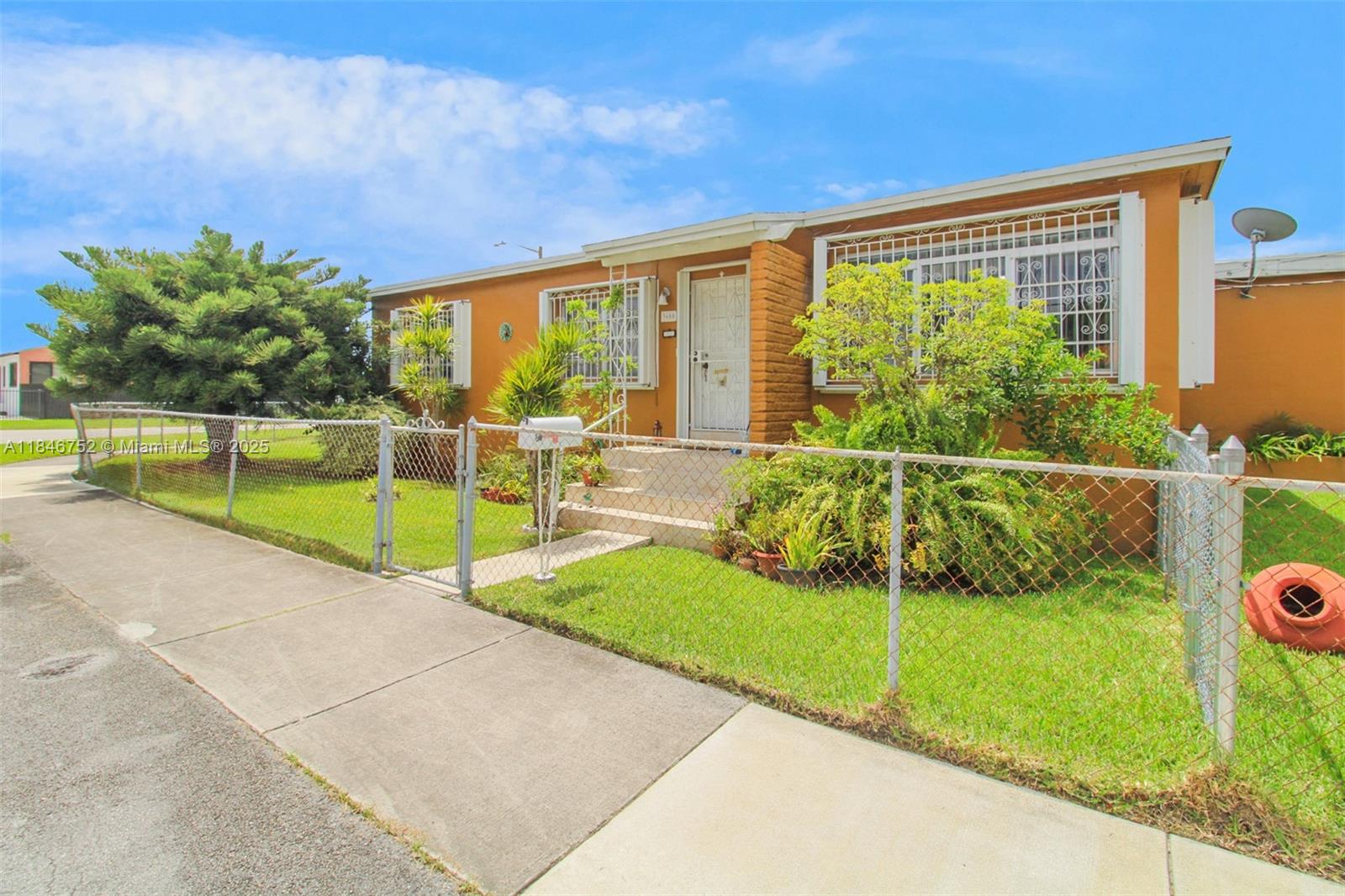 A single-story orange house with a chain-link fence and security bars on the windows — 3600 NW 19th Ter, Miami FL 33125, MIAMI, FL