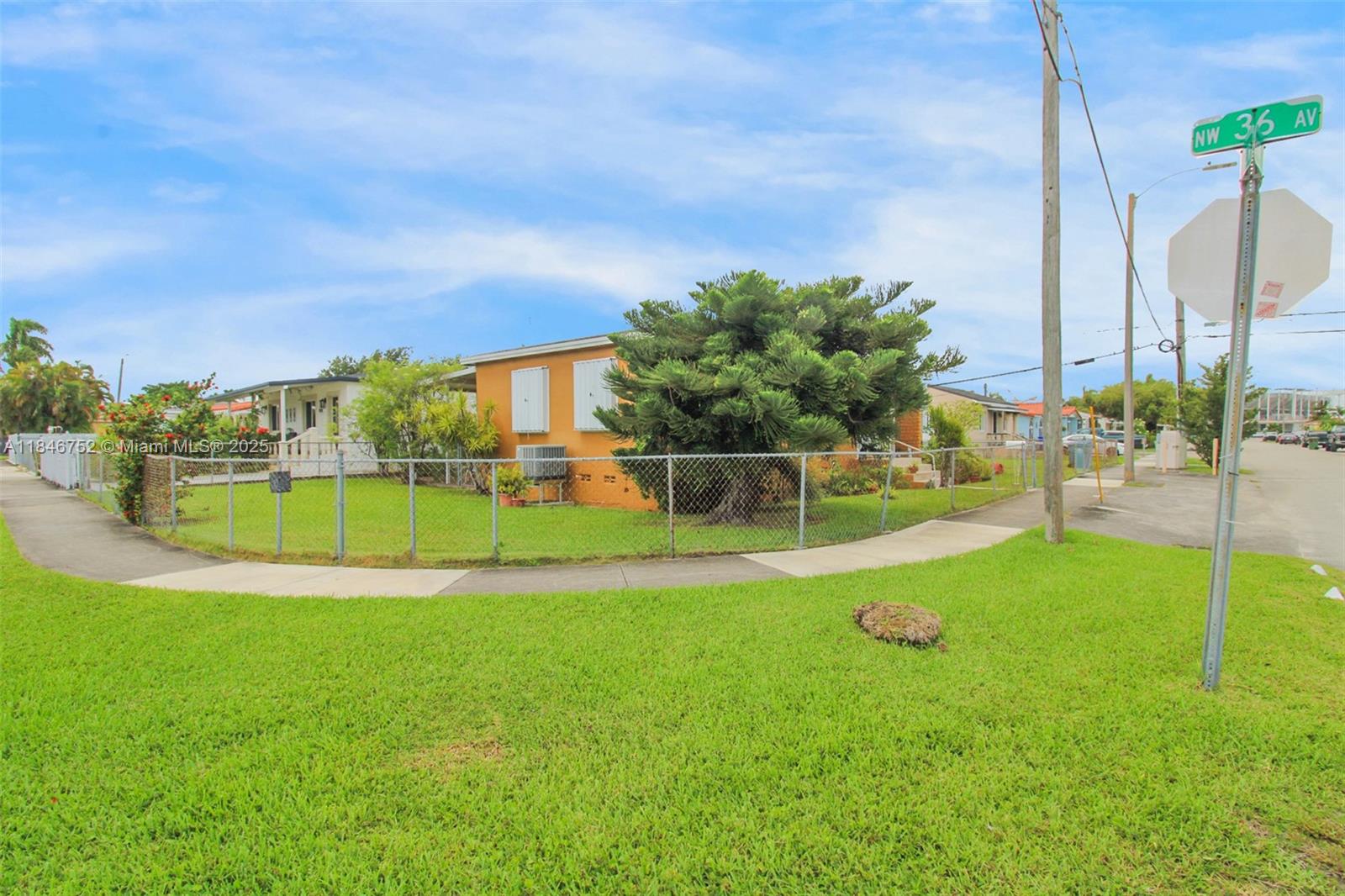 A single-story orange house sits on a corner lot behind a chain-link fence — 3600 NW 19th Ter, Miami FL 33125, MIAMI, FL