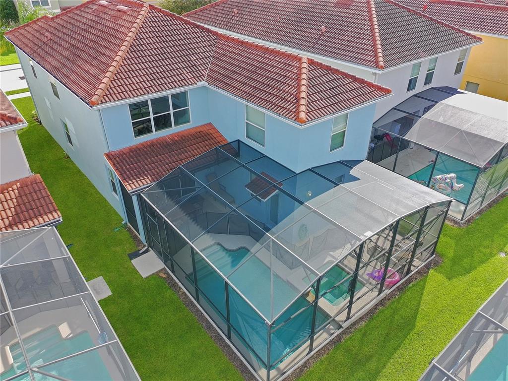 An aerial view shows a two-story house with a tiled roof and a screened pool enclosure — 2942 BUCCANEER PALM ROAD, KISSIMMEE, FL