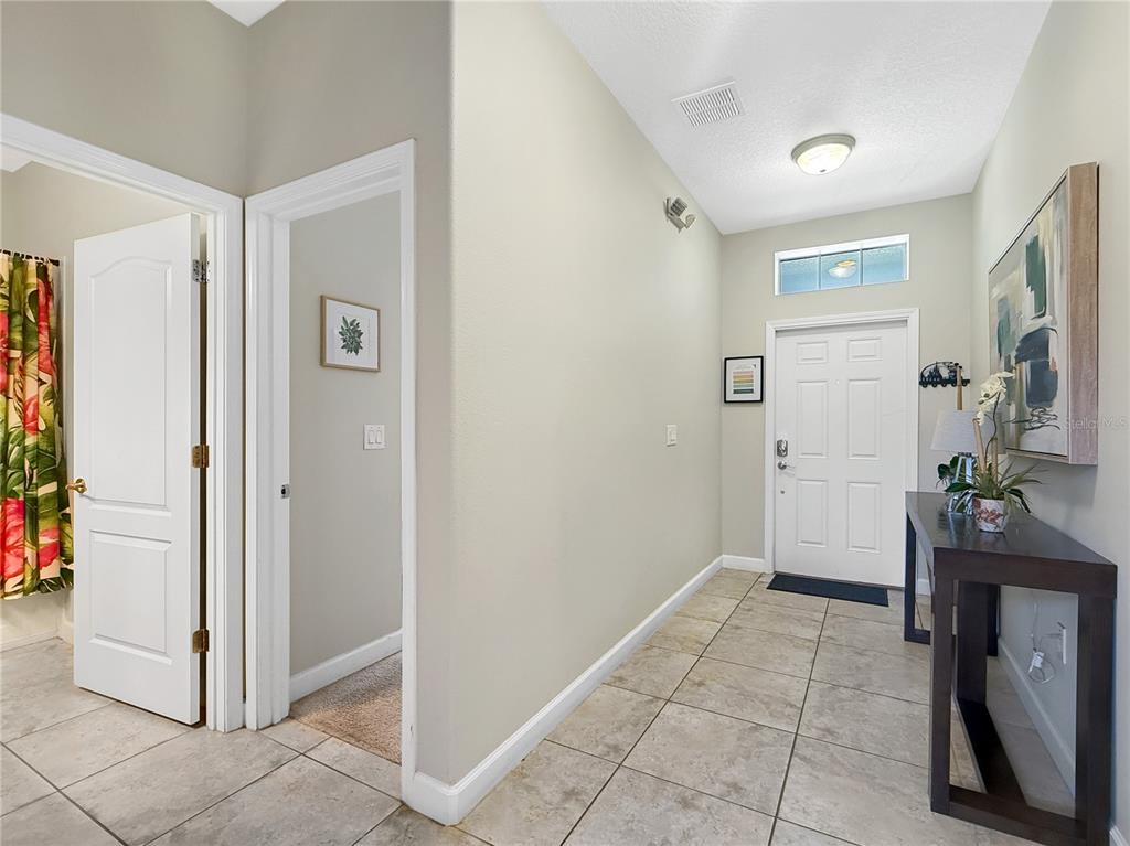 A tiled entryway features a white front door, a dark console table, and neutral walls — 2942 BUCCANEER PALM ROAD, KISSIMMEE, FL