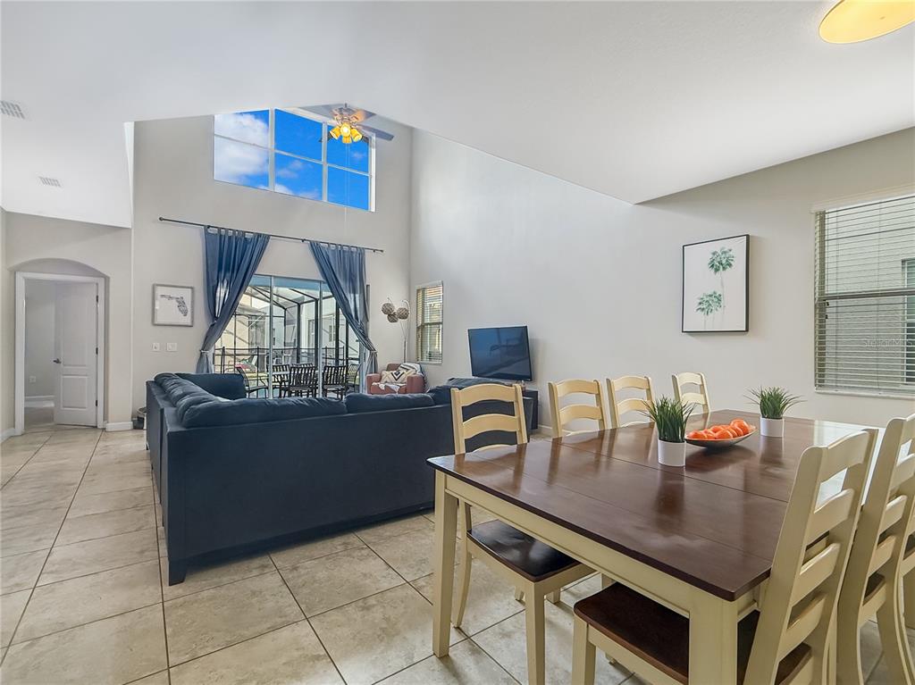 A living and dining area features vaulted ceilings, tile flooring, and a sliding glass door — 2942 BUCCANEER PALM ROAD, KISSIMMEE, FL