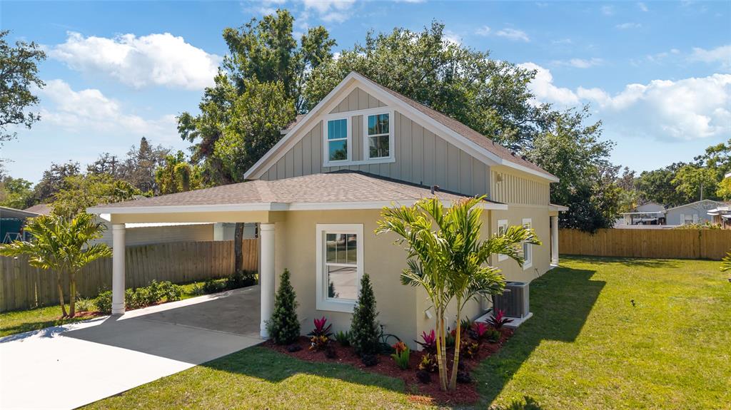 An exterior view of a tan house with a carport and a small landscaped front yard — 23 N EDWARDS STREET, PLANT CITY, FL