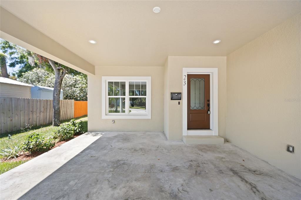 A covered concrete porch features a brown front door, a window, and recessed ceiling lighting — 23 N EDWARDS STREET, PLANT CITY, FL