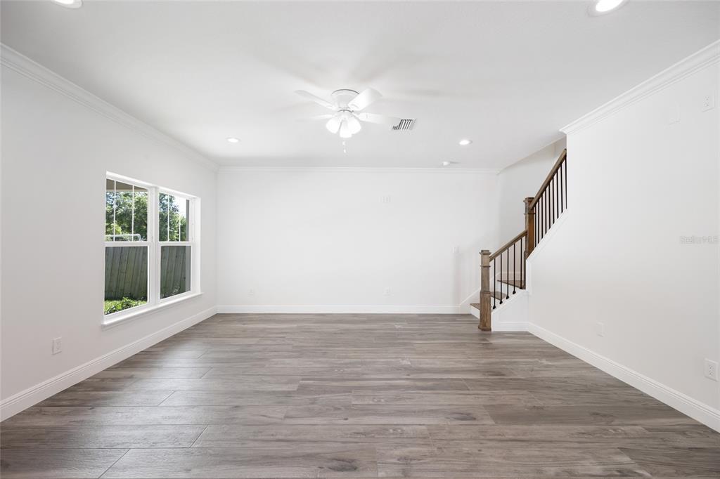 An empty living room with wood-look flooring, a ceiling fan, and a staircase with railings — 23 N EDWARDS STREET, PLANT CITY, FL
