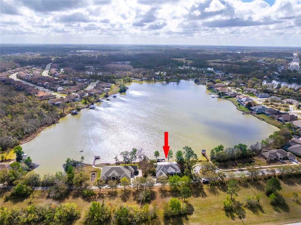 An aerial view of a blue house with a gray roof, solar panels, and waterfront access — 6716 MAGNOLIA POINT DRIVE, LAND O LAKES, FL