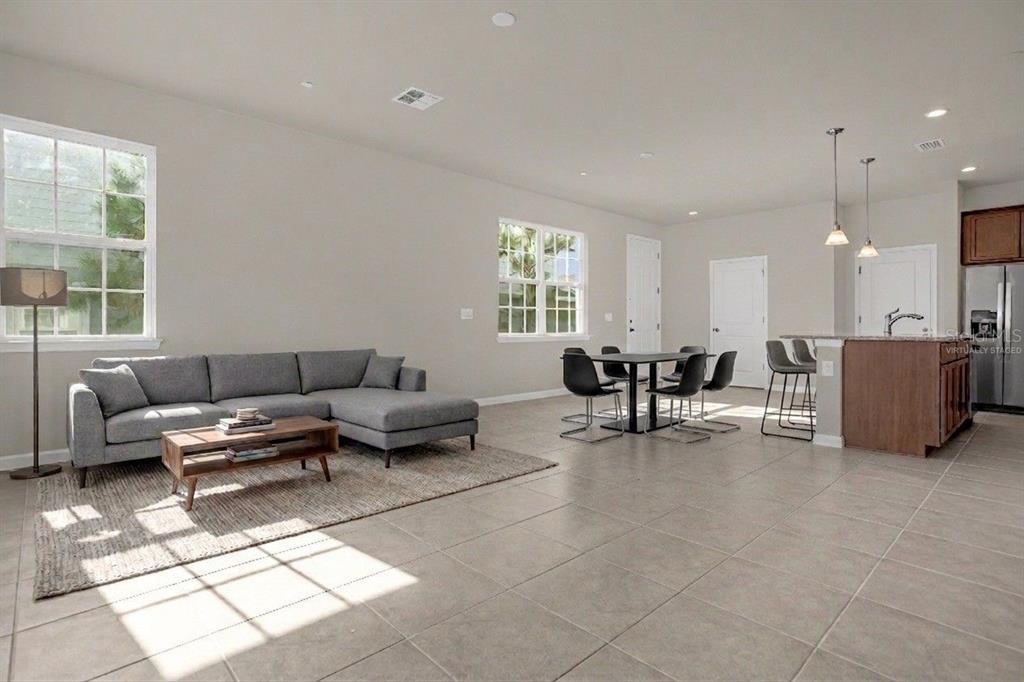 A living and dining area with tile floors, a gray sectional sofa, and kitchen island — 1926 HOLDEN RIDGE LANE, CLERMONT, FL