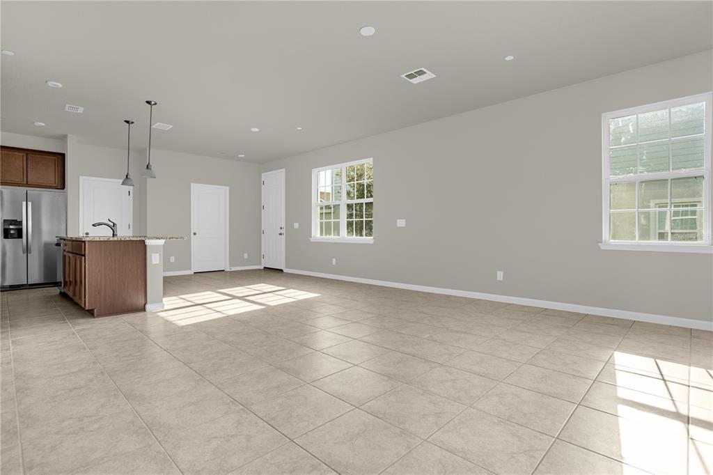 An open-concept kitchen and living area features tile flooring, neutral walls, and a kitchen island — 1926 HOLDEN RIDGE LANE, CLERMONT, FL