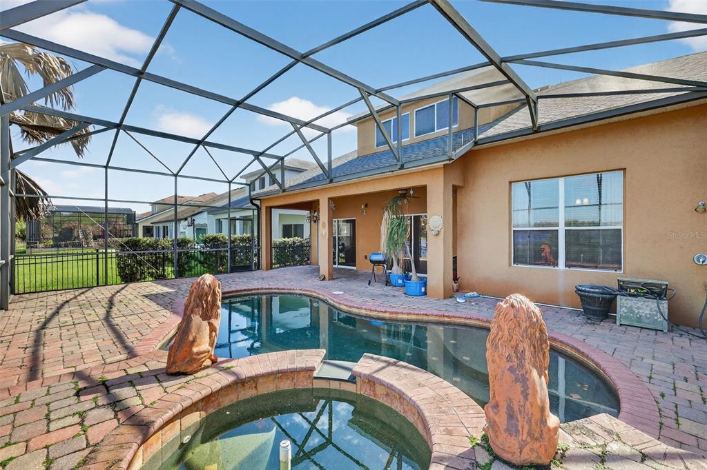 A screened-in patio features a swimming pool, a hot tub, and two lion statues — 5413 WALSH POND COURT, WINDERMERE, FL