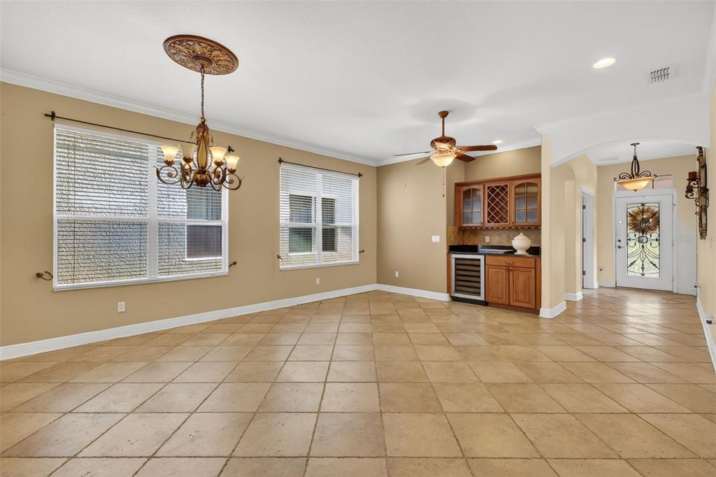 A spacious room with tan walls, tile flooring, a chandelier, and a built-in wet bar — 5413 WALSH POND COURT, WINDERMERE, FL