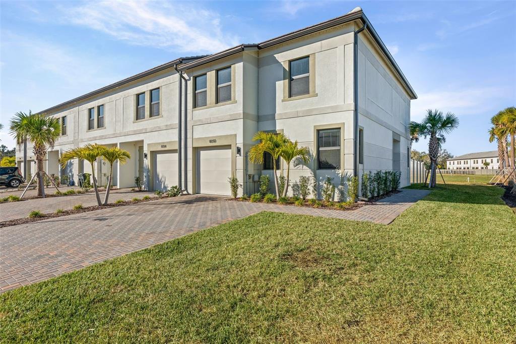 A two-story townhouse exterior with a paved driveway, garage, and palm trees on a lawn — 14506 STELLAR PLACE, LAKEWOOD RANCH, FL