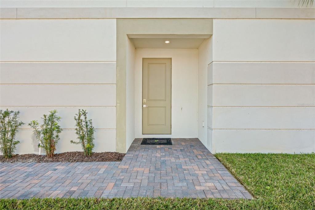 A tan front door is centered in a recessed entryway with a paver walkway — 14506 STELLAR PLACE, LAKEWOOD RANCH, FL