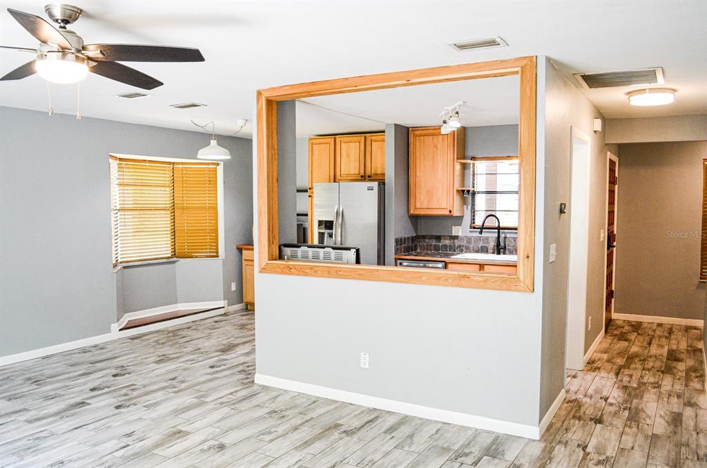 A kitchen with wood cabinets and stainless steel appliances is visible through a large wall opening — 3526 NW 53RD TERRACE, GAINESVILLE, FL