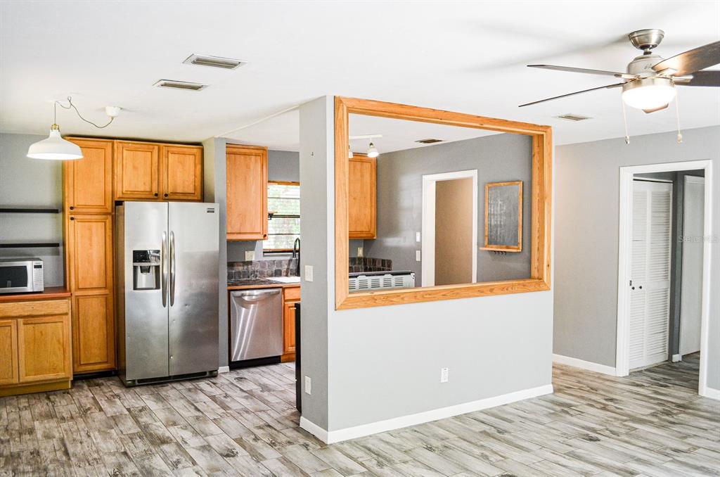 A kitchen with wood cabinets, stainless steel appliances, and a pass-through window to another room — 3526 NW 53RD TERRACE, GAINESVILLE, FL