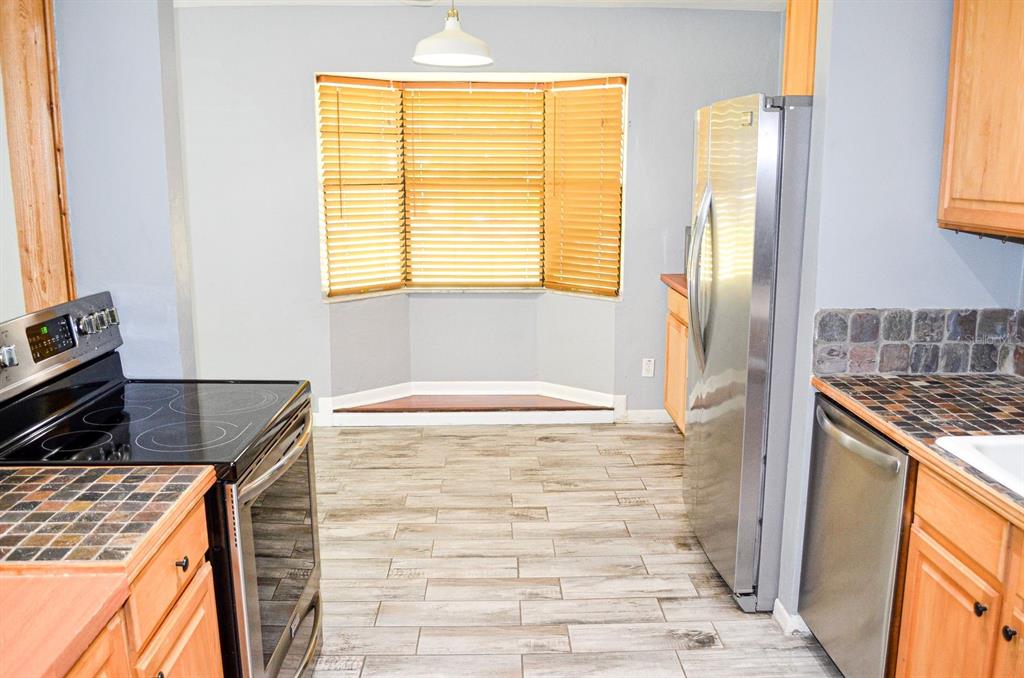 A kitchen with wood-look tile floors, stainless steel appliances, and a bay window seating area — 3526 NW 53RD TERRACE, GAINESVILLE, FL