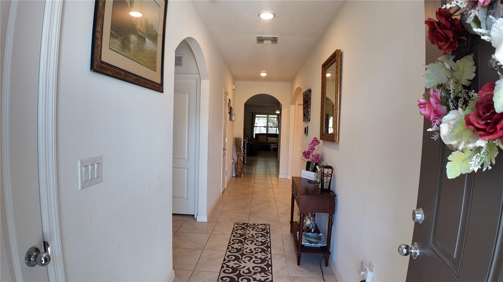 A tiled entryway leads into a hallway with arched doorways and a wooden console table — 35045 SWEET LEAF LANE, LEESBURG, FL