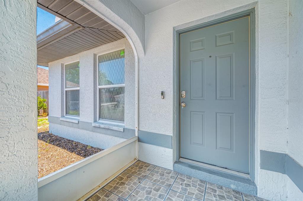 A covered front porch with tiled flooring leads to a light blue front door — 2802 93RD COURT E, PALMETTO, FL