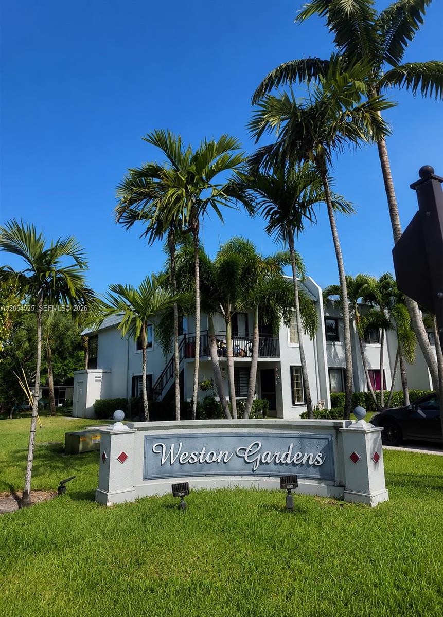 A sign for Weston Gardens stands in front of a two-story apartment building with palm trees — 16571 Blatt Blvd # 203, Weston FL 33326, WESTON, FL